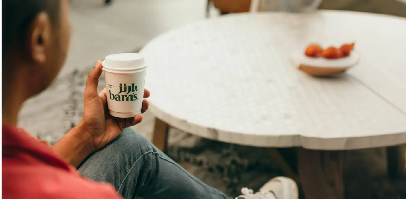 Guest holding a Barn's cup at a table